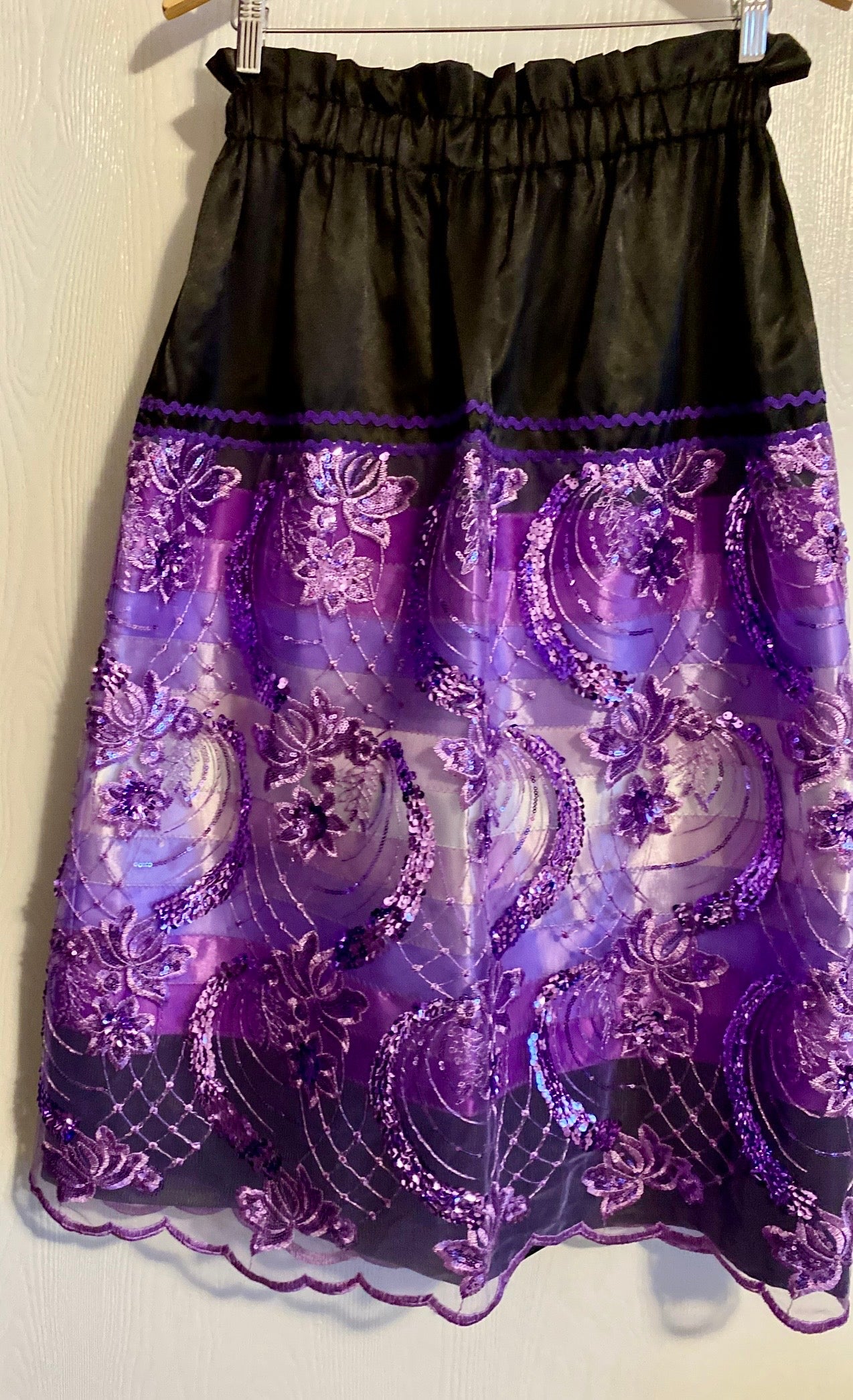 Black skirt with purple lace details on a white background with purple ribbons. Purple ribbon skirt