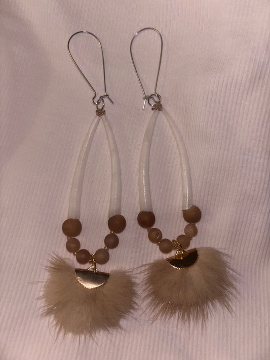 Dentalium shell Pair of earrings with brown beads and feather-like ends on a light background